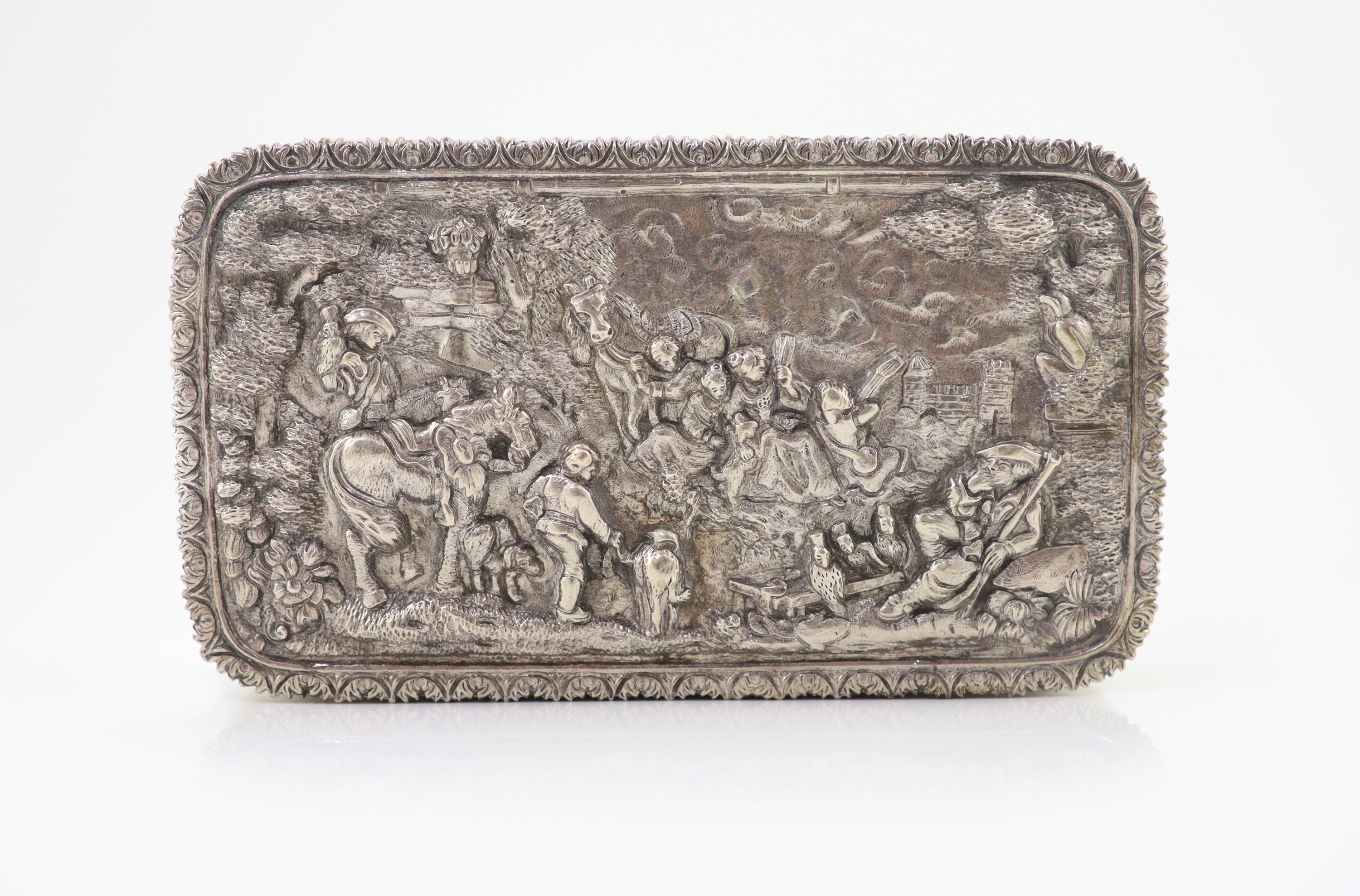 A 20th century Portuguese 833 standard silver rectangular box and cover, the lid cast and chased in high relief with travellers approaching a town,